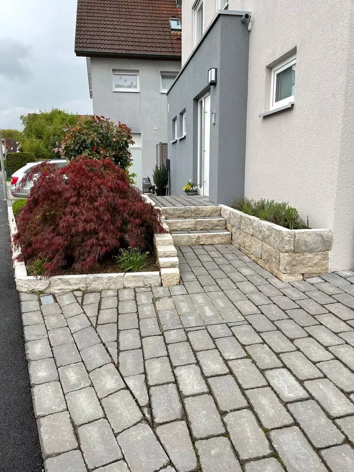 Nachher: fertiger Hauseingang mit Treppe, Mauer und Bepflanzung